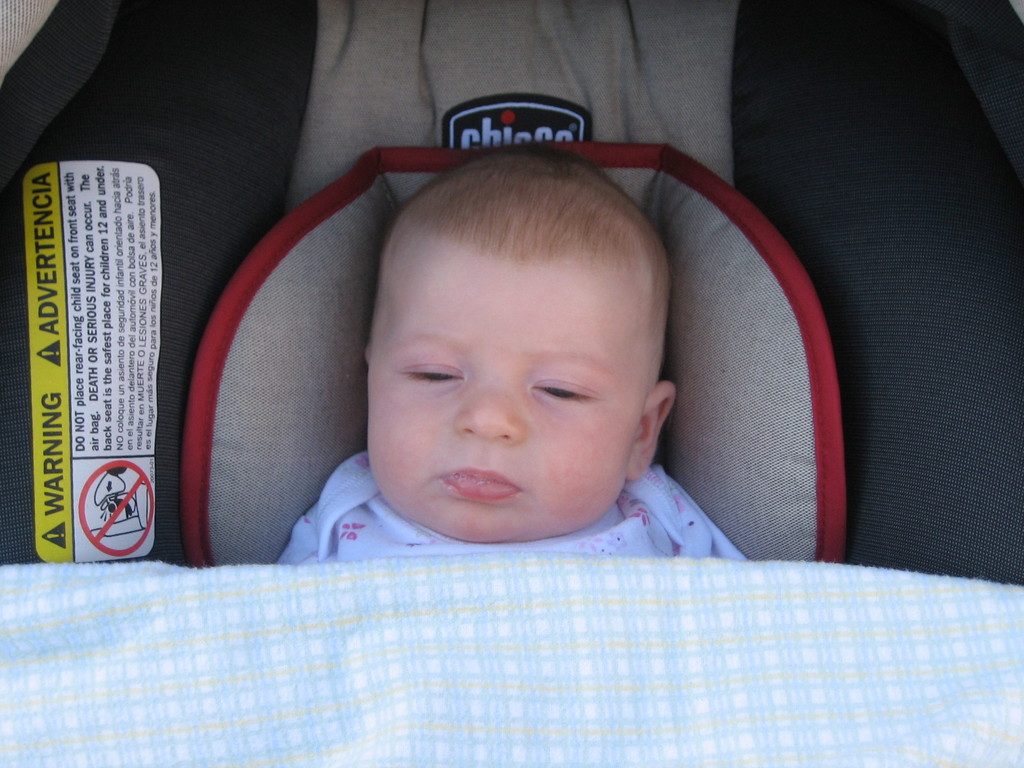 Ein Baby unter einer Babyschaukel mit einem Warnaufkleber auf der linken Seite der Schaukel.