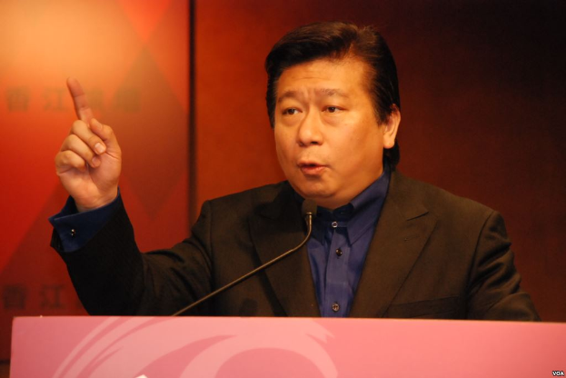 Ein Mann im Anzug und Krawatte hält eine Rede an einem Rednerpult mit Mikrofon und sieht ernst und professionell aus.