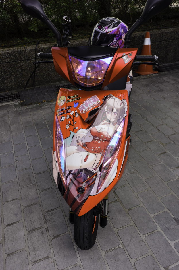 Ein oranges E-Scooter auf der Straße geparkt mit einem Helm darauf, mit einer Verkehrskegel, einer Wand und Bäumen im Hintergrund.