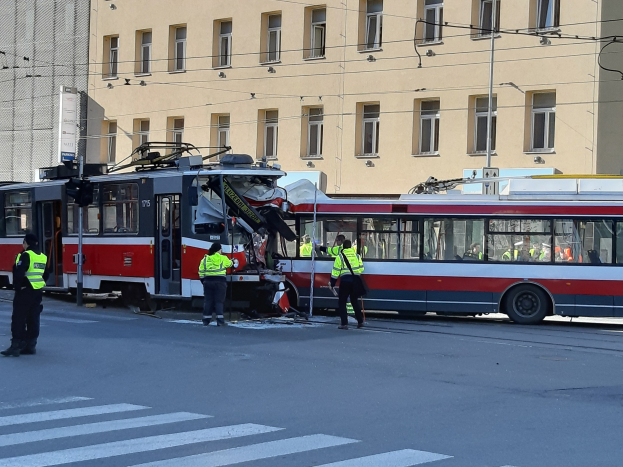 Rote und weiße Tram in einen Straßenunfall verwickelt mit wenigen Menschen in der Nähe und einem Gebäude im Hintergrund.