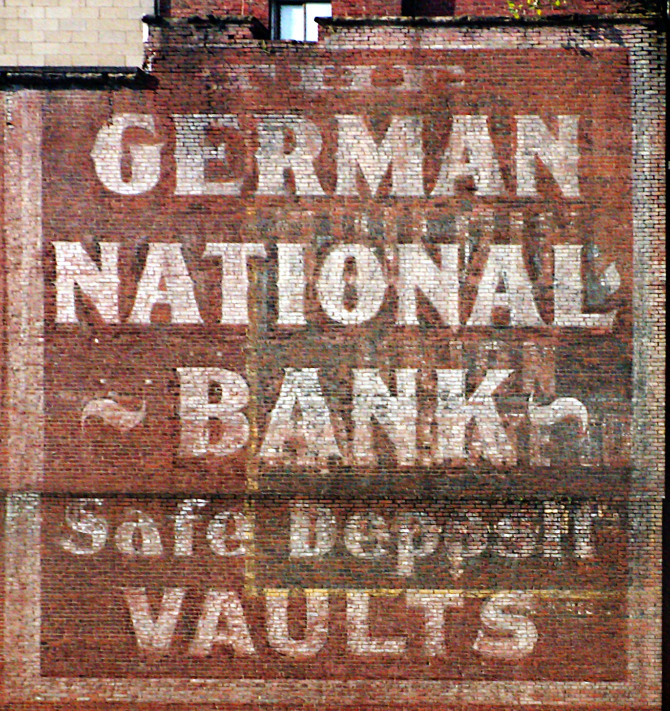 Eine Ziegelwand mit einem Schild, das "Deutsche Nationalbank-Schließfächer" und ein Fenster oben zeigt.