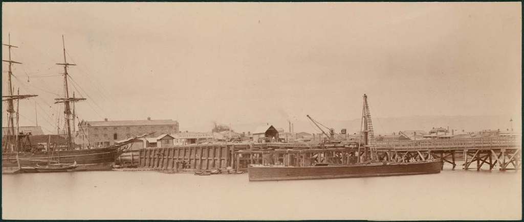 Eine Szene mit Wasser, Booten, Gebäuden, Strommasten und einem Himmel.