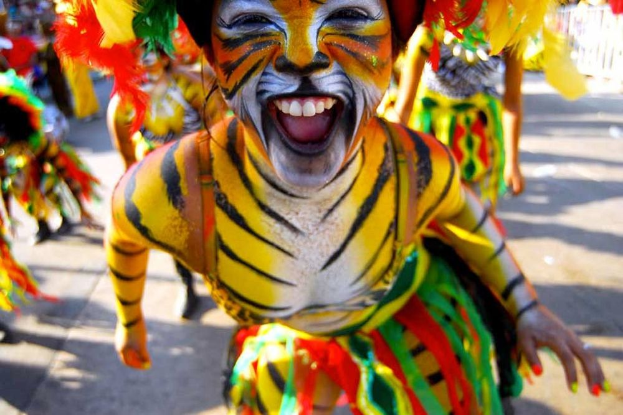 Eine Gruppe von Menschen in bunten Kostümen und Schminke, mit einer Frau in einem Tigerkostüm bei einem Karneval, mit einem unscharfen Hintergrund.