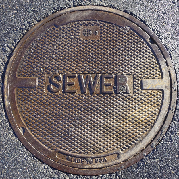 Metallschachtdeckel auf der Straße mit der eingravierten Aufschrift "Kanal"