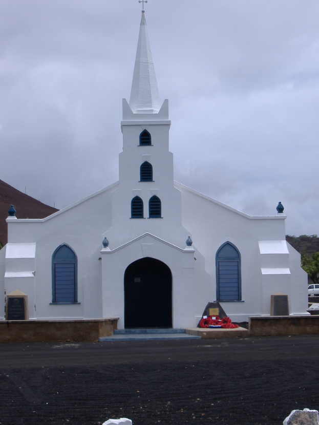 Eine Kirche in der Mitte des Bildes mit einer Straße unten, Bäumen und einem Auto im Hintergrund.
