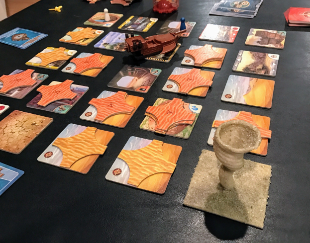 Ein unordentlicher Tisch mit Star Wars: The Old Republic-Spielkarten, Spielzeugen und Gegenständen in einem Raum mit einer Wand im Hintergrund.