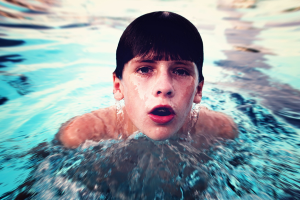 Ein Junge schwimmt in der Mitte eines Gewässers.