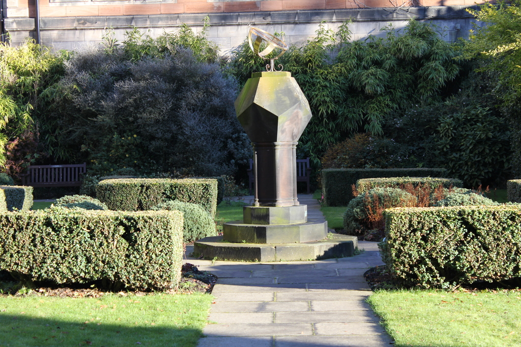 Eine Parkszene mit verschiedenen Pflanzen, Bäumen und einem einzelnen Mast.