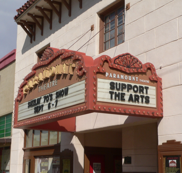 Außenansicht des Paramount Theatre in Sacramento, Kalifornien, mit Glasfenstern und -türen, einem "Support the Arts"-Schild und dem Himmel im Hintergrund.