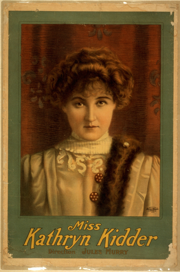 Ein altes Foto einer Frau mit warmem Lächeln, die ein weißes Kleid und ein gemustertes Tuch trägt, ihr Haar ist zu einem Knoten gebunden und sie schaut direkt in die Kamera mit dem Text "Miss Kathryn Kidder" unten.