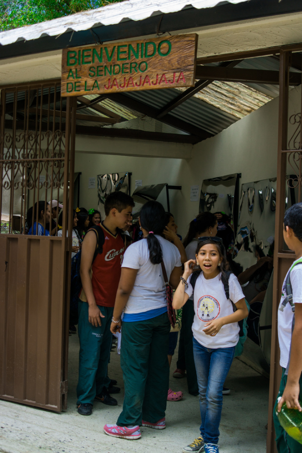Ein Geschäft mit einem Eisenblechdach, das ein Schild mit Text oben drauf und Menschen drinnen zeigt.