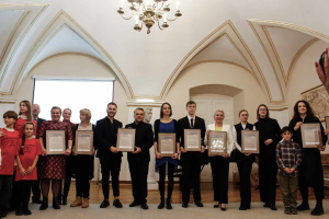 Eine Gruppe von Menschen steht nebeneinander in einem Raum, jeder hält ein Zertifikat in der Hand, mit einer Hand auf der rechten Seite, einer Wand, einer Tür, einem Bildschirm und einem Kronleuchter im Hintergrund bei einer Preisverleihung für das akademische Jahr 2018-2019.