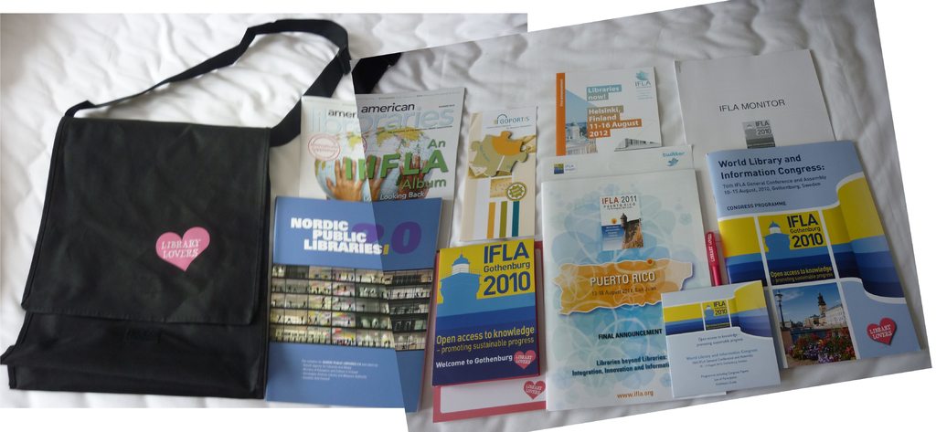 Eine Tasche mit "Bibliotheksliebhaber" darauf und einige Bücher auf einem Bett.