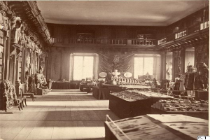 Schwarz-weiß-Fotografie eines Museumsraums mit zahlreichen Tischen, Stühlen, Skulpturen an den Wänden, Fenstern, Vorhängen und Geländern, beschriftet mit "The Museum of Fine Arts, London" unten.