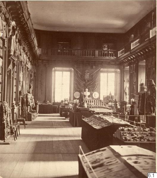 Schwarz-weiß-Fotografie eines Museumsraums mit zahlreichen Tischen, Stühlen, Skulpturen an den Wänden, Fenstern, Vorhängen und Geländern, beschriftet mit "The Museum of Fine Arts, London" unten.