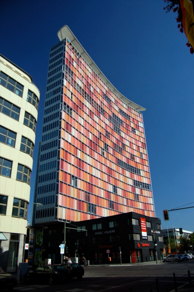 Hohe Gebäude mit parkenden Autos in einer Parklücke und ein Verkehrsampelmast auf der rechten unteren Seite.