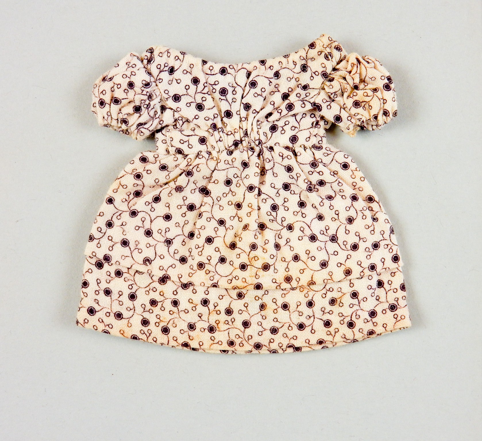 Weißes knielanges Sommerkleid mit rundem Halsausschnitt, kurzen Ärmeln und einem Volantrock, das ein komplexes, farbenfrohes Muster auf einem leichten Stoff hat, auf einer weißen Oberfläche präsentiert.