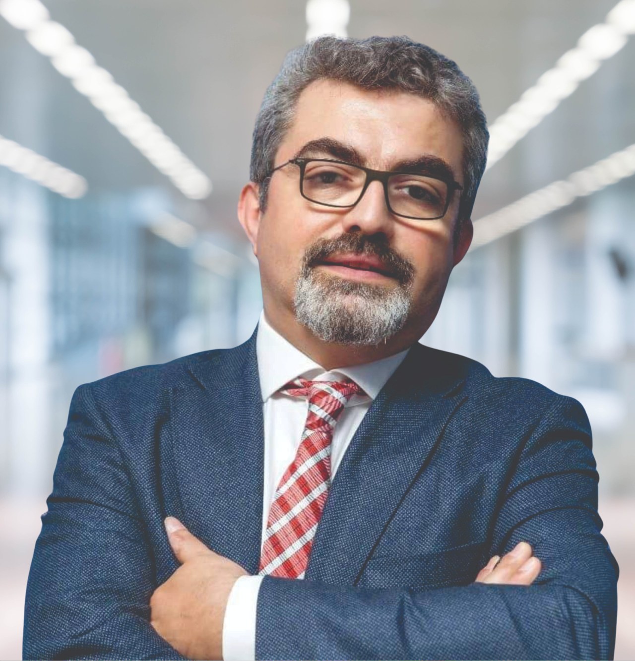 Ein Mann in Anzug und Krawatte mit verschränkten Armen und Brille, der vor einem unscharfen Hintergrund steht, auf dem steht, dass er der neu ernannte Marketingchef ist.