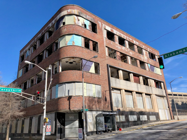 Altes Backsteingebäude an einer Straßenecke, ehemaliger Hauptsitz der University of Illinois at Chicago, mit Straßeninfrastruktur und Fahrzeugen im Hintergrund.