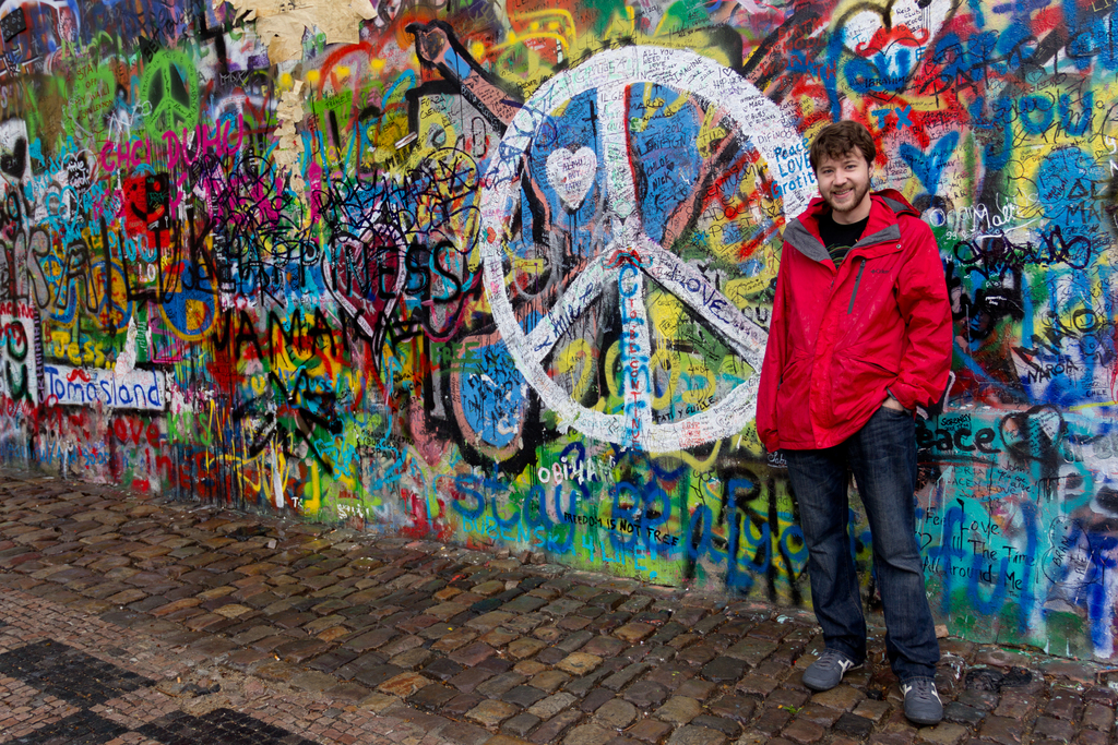 Eine Person steht vor einer Wand mit Graffiti, mit einem Gehweg unten.