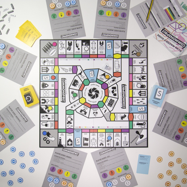 Ein Monopoly-Brettspiel auf einem Tisch mit Spielkarten, Papieren und einem Bleistift, der um das Spielbrett und seine Teile herum verstreut ist.