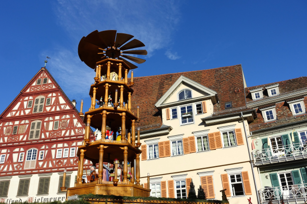 Ein festliches Weihnachtsmarkt-Szenario in Rothenburg ob der Tauber, Deutschland, mit einem hölzernen Aufbau mit Windmühle, Menschen, Pflanzen und anderen Gegenständen, mit dem Himmel im Hintergrund.