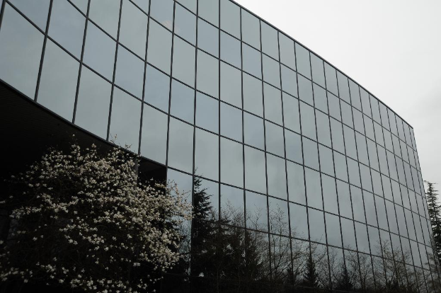 Ein modernes Gebäude mit Glasfassaden, umgeben von Bäumen, unter einem klaren Himmel.