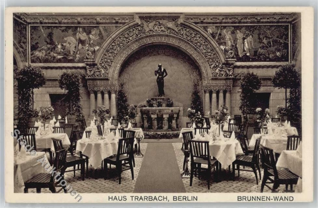 Schwarz-weißes Foto eines alten Berliner Restaurant-Interieurs mit Tischen, Stühlen, Blumenvasen, Skulpturen, Pflanzen und einer Statue im Hintergrund.