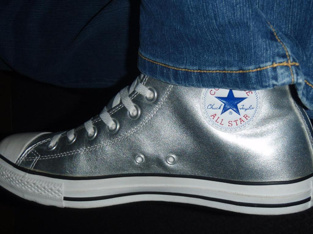 Ein Schuh mit Text und Schnürsenkeln, mit dem Rand von Jeans in der oberen rechten Ecke, vor einem dunklen Hintergrund.