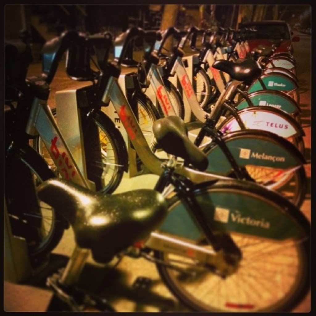 Mehrere Fahrräder sind in der Mitte des Bildes geparkt, hinter ihnen ist ein Fahrzeug zu sehen.