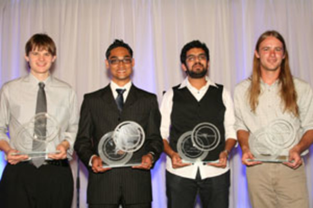 Vier Personen mit strahlenden Gesichtern halten je einen Pokal in der Hand, vor einem Vorhang.
