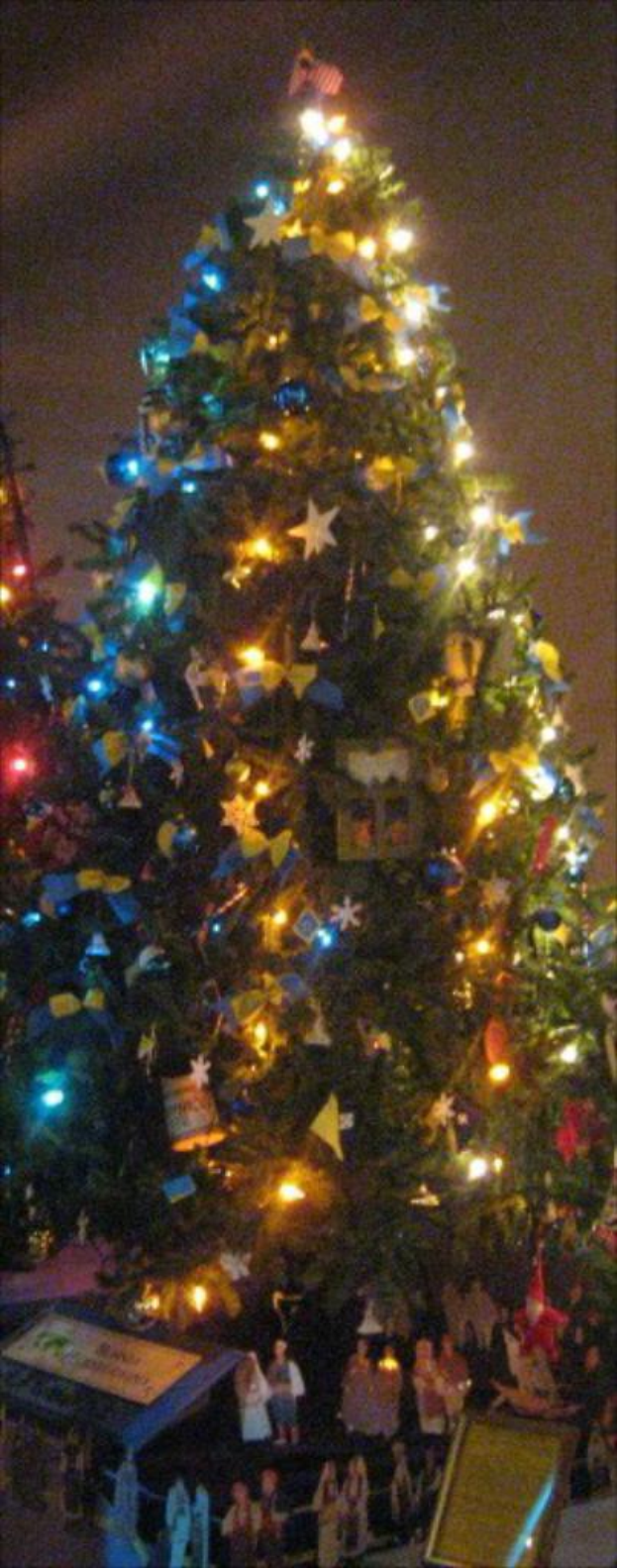 Ein geschmückter Weihnachtsbaum mit darunter platzierten Menschenfiguren auf einem Tisch.