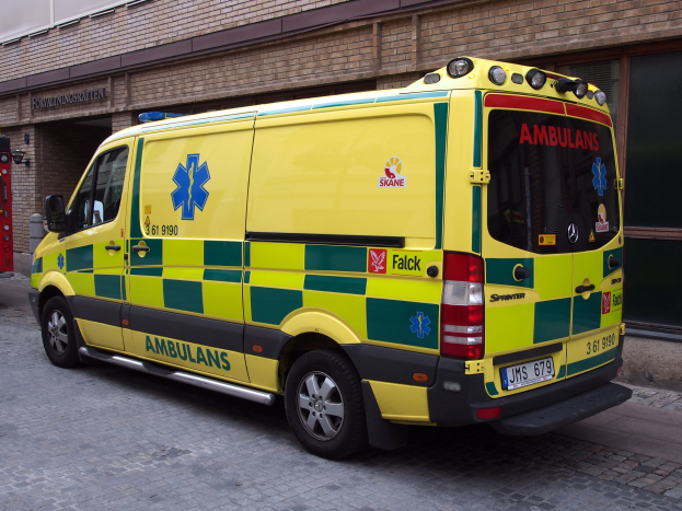 Ambulanz vor einem Backsteingebäude auf der Straße geparkt mit Text, mit einem Feuerlöscher auf der linken Seite sichtbar.