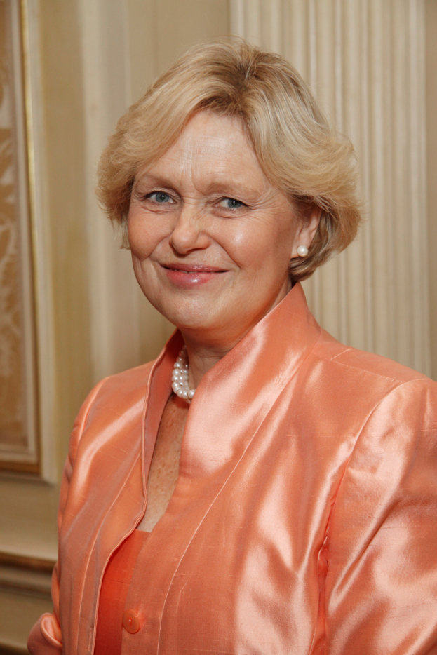 Eine Frau in einem orangen Kleid mit einem Foto im Hintergrund.