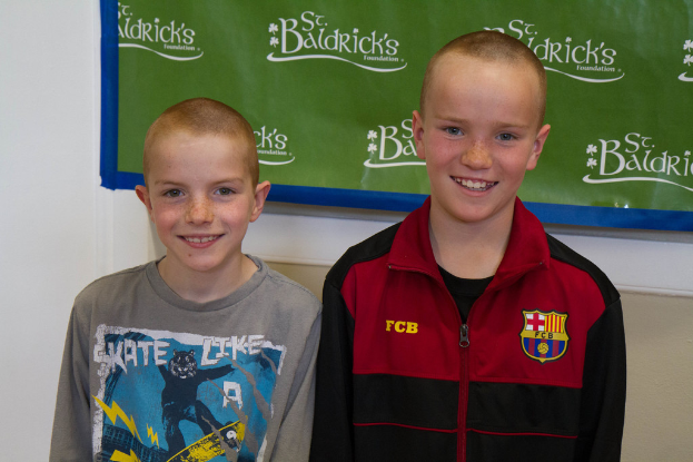 Zwei Jungen, die zusammenstehen und lächeln, mit einem Banner im Hintergrund mit Text.