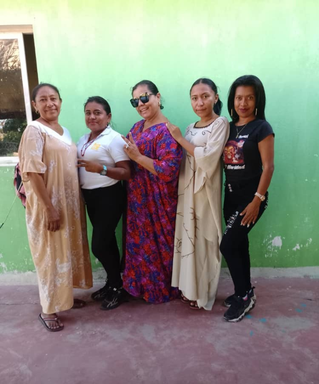 Gruppe von Frauen vor einer grünen Wand mit einem Fenster, die an einem Internationalen Frauentag teilnehmen.