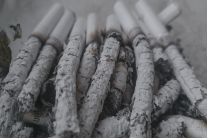 Ein unordentliches Häufchen aschgrauer Zigaretten auf einem Tisch.