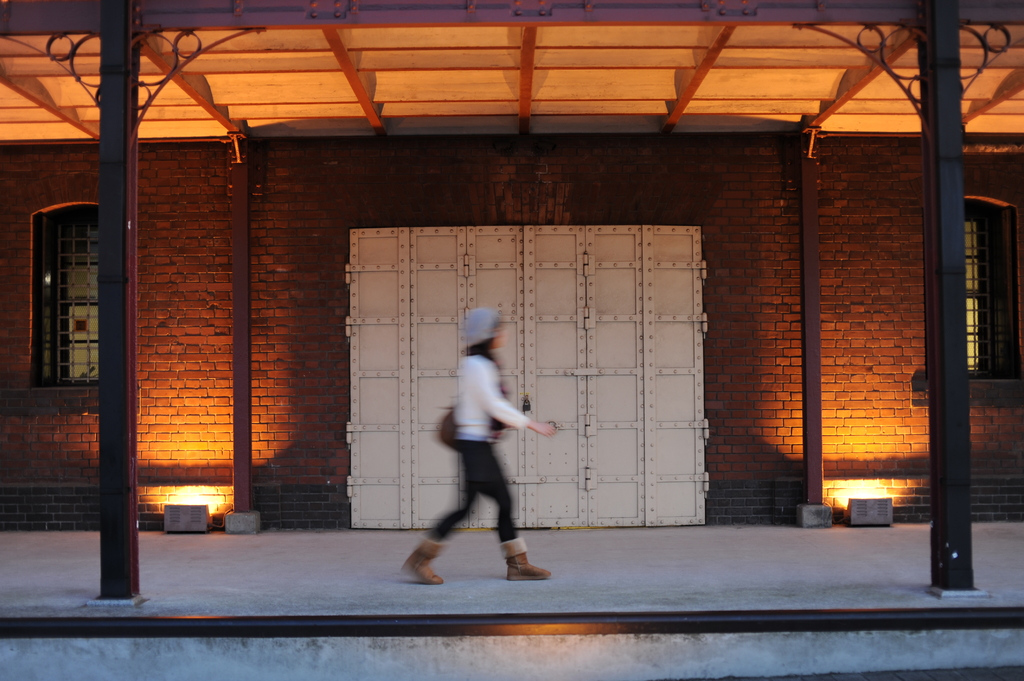 Ein Gebäude mit einer Metalltür und einer Frau, die durch den Flur geht.