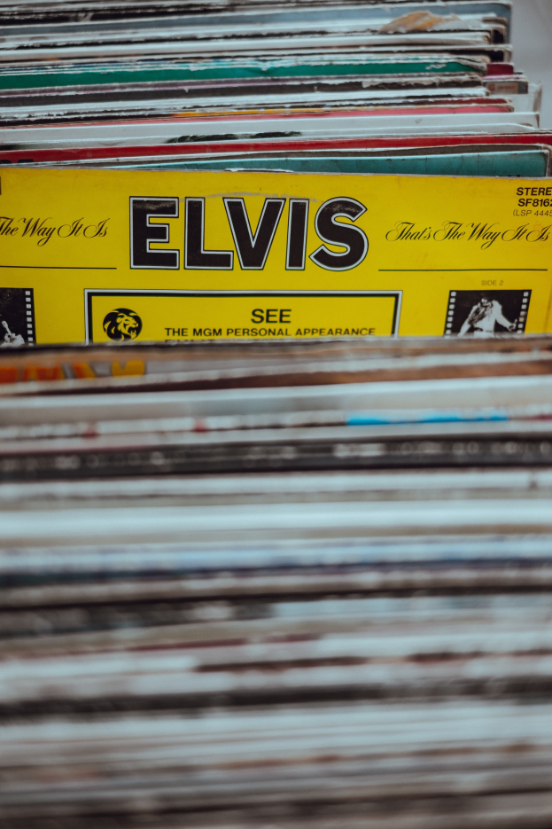 Ein ordentlich gestapelter Stapel von Elvis Presley-Platten mit sichtbaren Titeln auf einem leicht unscharfen Hintergrund.