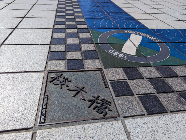 Ein gefliesteter Boden mit einem Schild, auf dem "Yokohama" steht, und eine Tafel mit Text darauf.