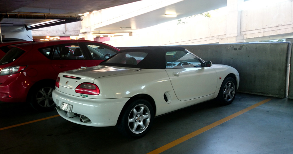 Autos in einem Keller mit einem Rohr am Dach und einem weiteren Gebäude oben rechts.
