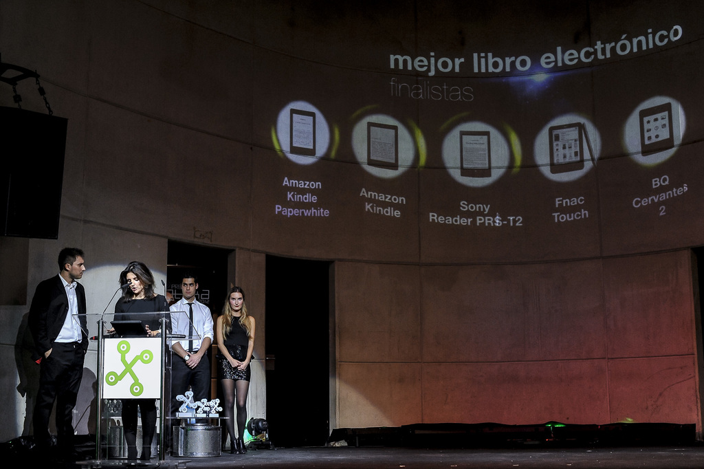 Vier Personen auf der linken Seite, eine Frau hält einen Vortrag, mit Bildern von Geräten und ihren Namen im Hintergrund.