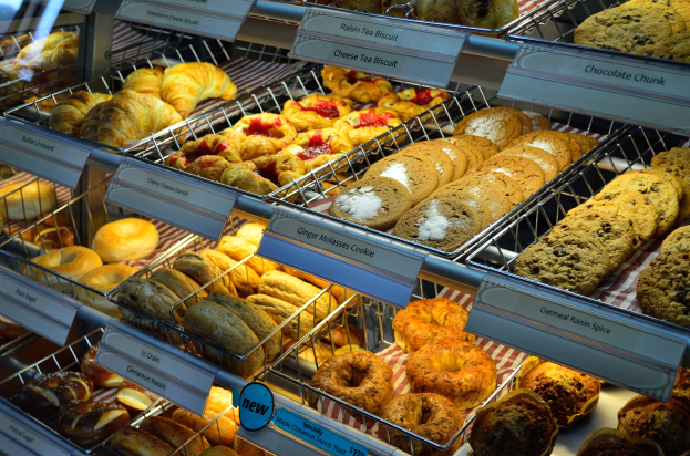 Ein Bäckereischaufenster voller verschiedener Keks-, Kuchen-, Plätzchen- und anderen Backwaren, mit Schildern, die die Art der Backwaren angeben.