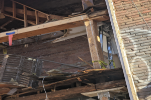 Teilweise abgerissenes Gebäude mit verstreuter Trümmer, zerbrochene Fenster und Türen nach Abriss.