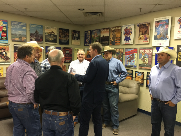 Gruppe von Männern in einem Raum mit Sofas, Plakaten an den Wänden und Deckenleuchten, die sich unterhalten.