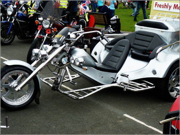 Viele Fahrräder vor der Stadt mit einer Frau auf einer Bank und einer Gruppe von Menschen im Hintergrund, die über eine Wiese gehen.