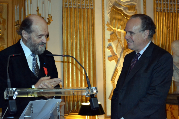 Ein Podium mit Mäusen oben drauf, ein lachender Mann rechts, eine Statue, ein Kerzenständer und eine Wand mit Entwürfen im Hintergrund.