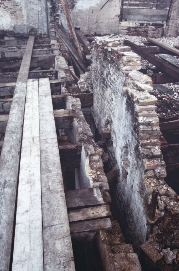 Altbau wird abgerissen mit verstreuten Holzplanken und Steinen im Vordergrund und einer remaining Wand im Hintergrund.