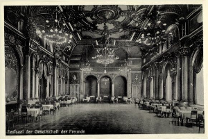 Schwarzes und weißes Foto eines großen Raums mit Tischen, Stühlen, Säulen, Bögen und Kronleuchtern an der Decke, beschriftet mit "Fest der Gesellschaft der Freunde, Berlin" unten.
