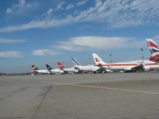 Eine Start- und Landebahn mit wenigen Flugzeugen, Pfählen, Kabeln und einer bewölkten Himmel
